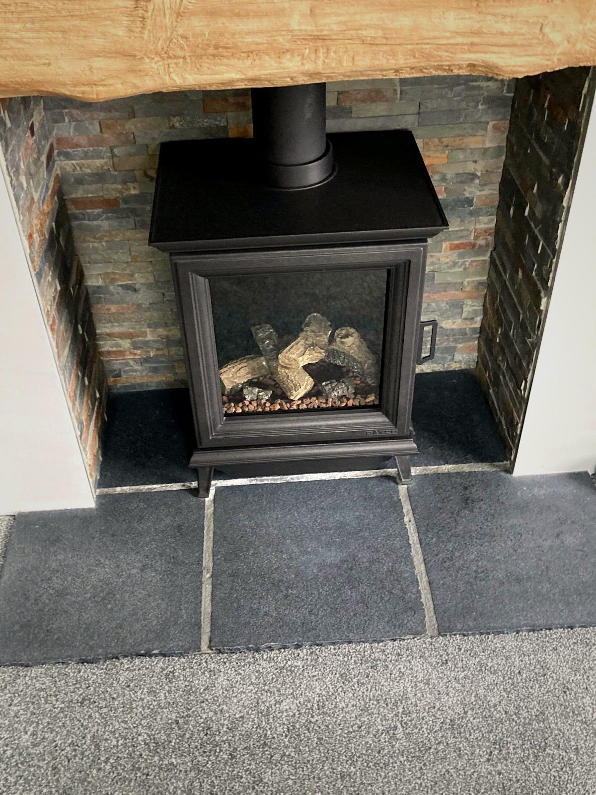 A solid-fuel stove in a brick inglenook with a timber lintel
